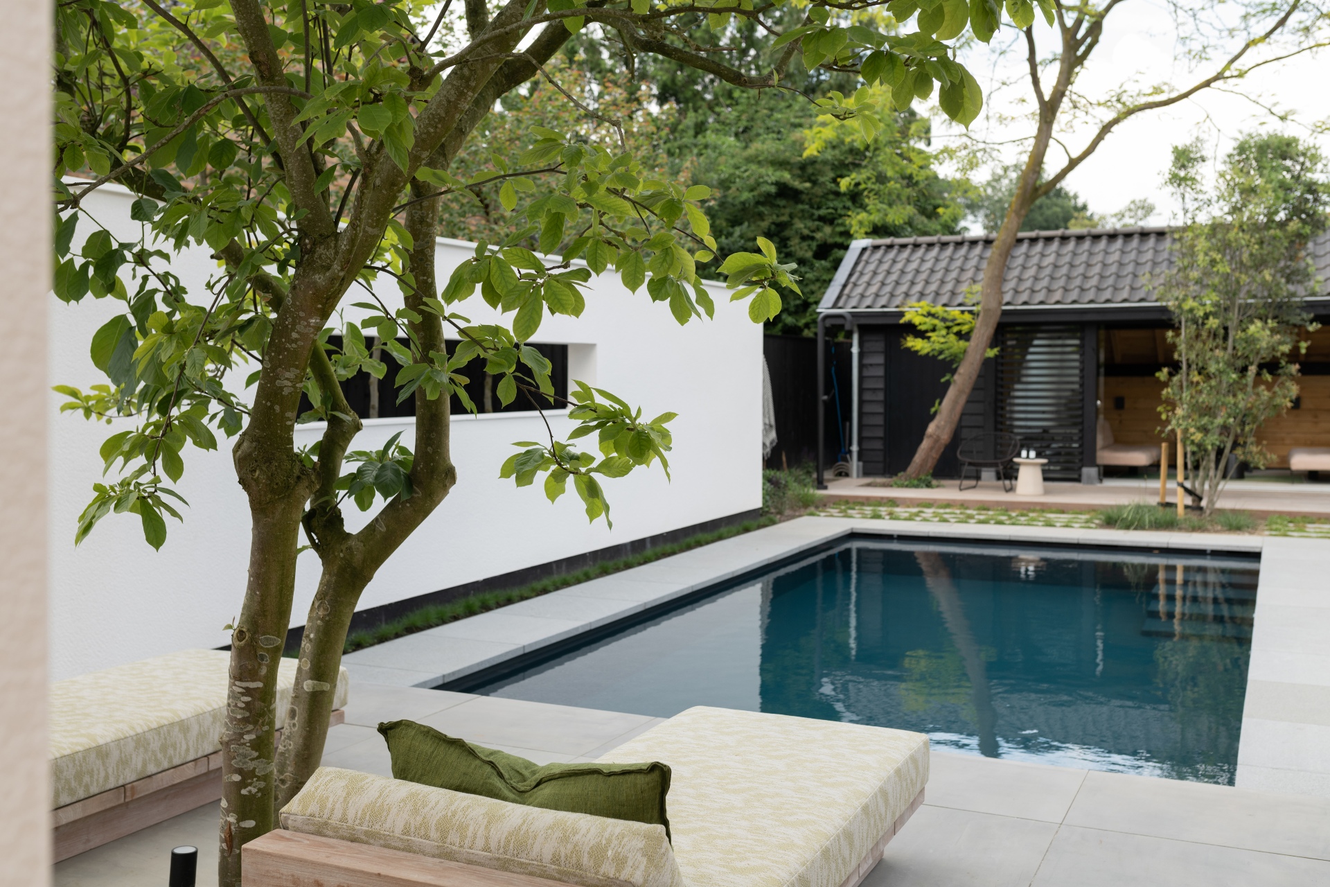 Donkergrijs inbouwzwembad met poolhouse en grijze tegels in moderne tuin